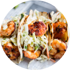 Grilled shrimp tacos with cabbage slaw on a gray plate.