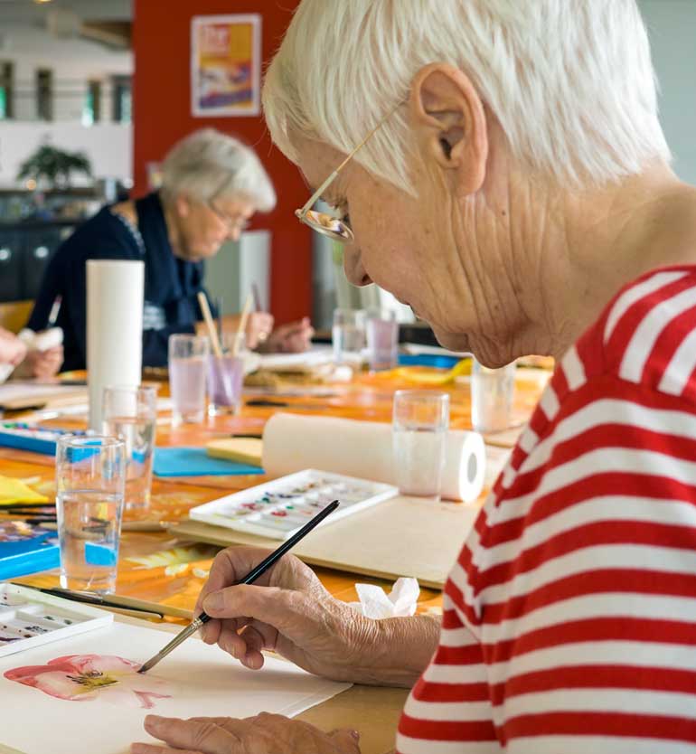 Residents painting together during an arts and crafts activity in a senior living community.