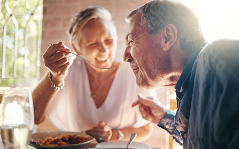 Elderly couple enjoying a meal together in a communal dining area.