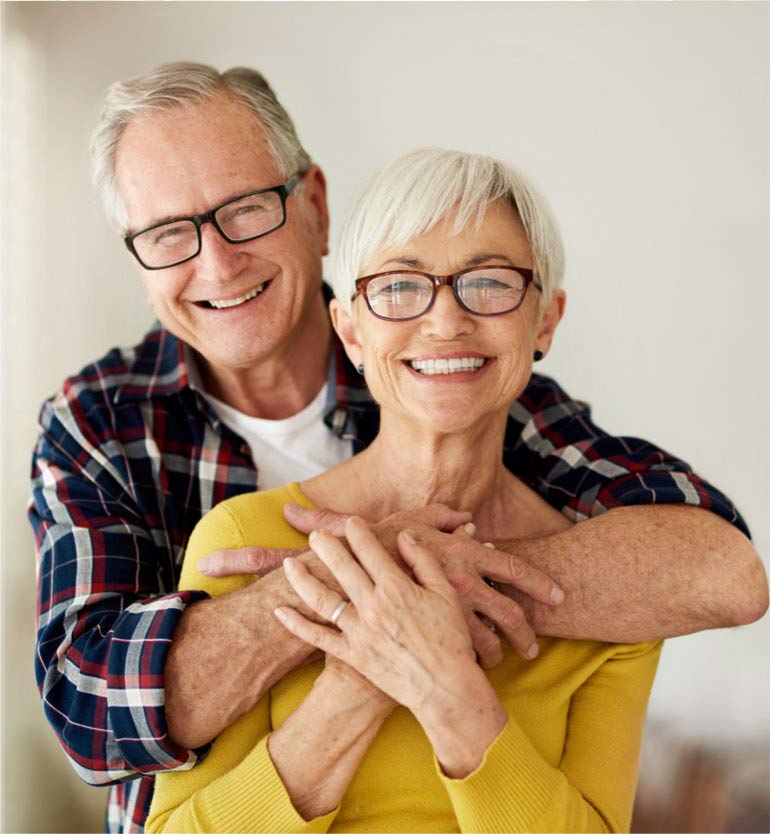 Smiling senior couple embracing each other warmly inside a bright living space.