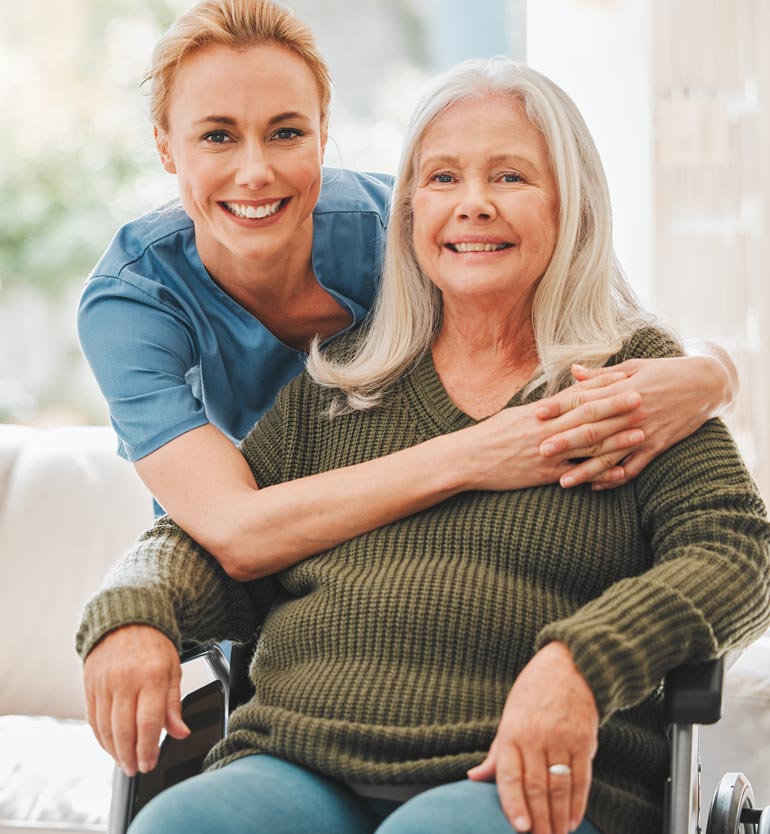 Happy senior woman in wheelchair with supportive healthcare worker in a bright room.